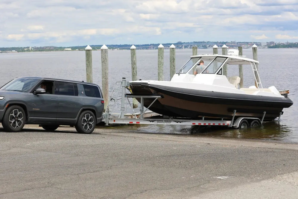 SUV towing Hyfoil 32 Electric Boat on a trailer by a dock with water and sky in the background