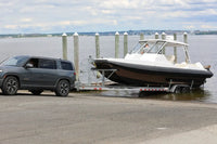 SUV towing Hyfoil 32 Electric Boat on a trailer by a dock with water and sky in the background
