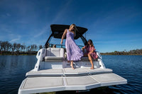 Two women on Ingenity 23e Electric Boat in a body of water with a clear sky.