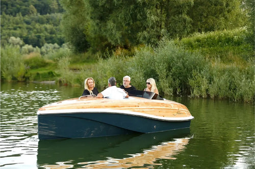 People on Nova Luxe Faro Electric Boat in a calm body of water with greenery in the background