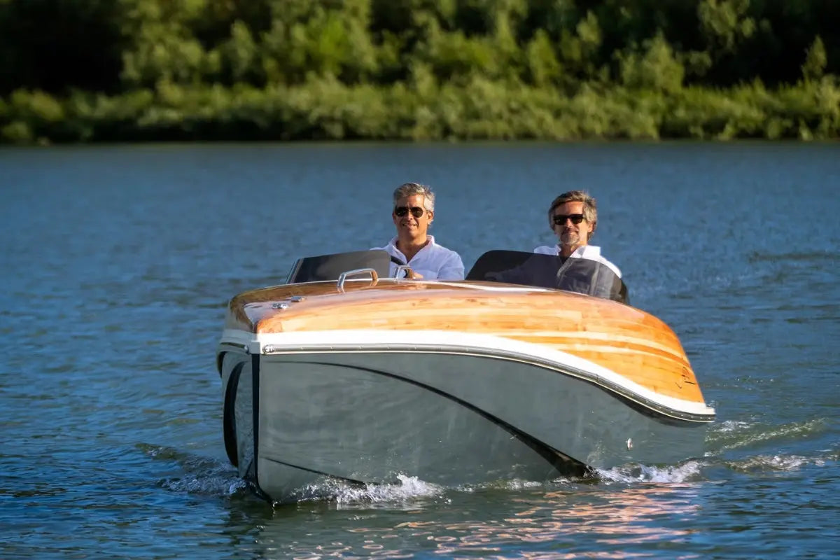 Two people in Nova Luxe Faro Electric Boat on a calm body of water with trees in the background