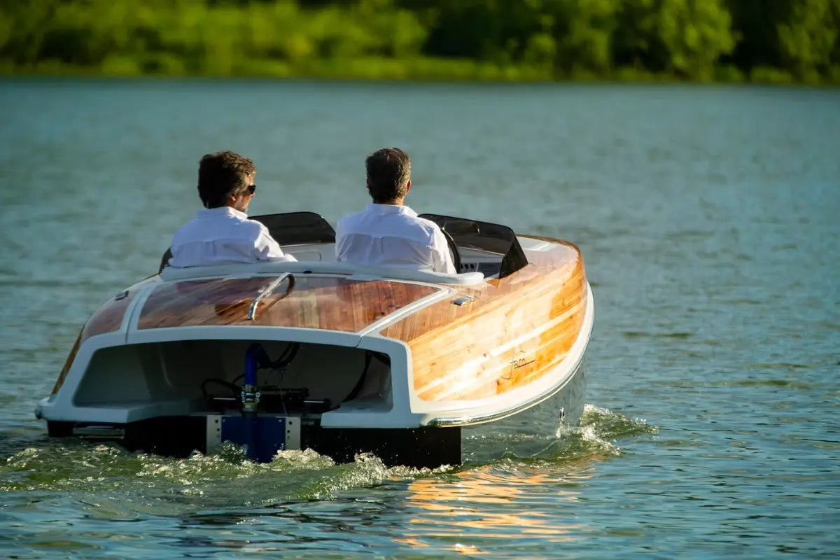 Two people in Nova Luxe Faro Electric Boat on a calm lake with greenery in the background