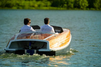 Two people in Nova Luxe Faro Electric Boat on a calm lake with greenery in the background