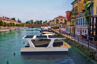 Floating Nova Luxe Faro Electric Boat with solar panels on a canal in an urban setting