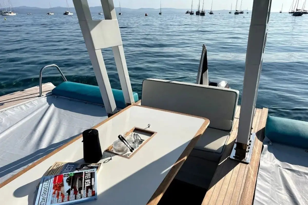 Nova Luxe Orphie 29 Electric Boat with a table and chairs on a calm sea with other boats in the distance.