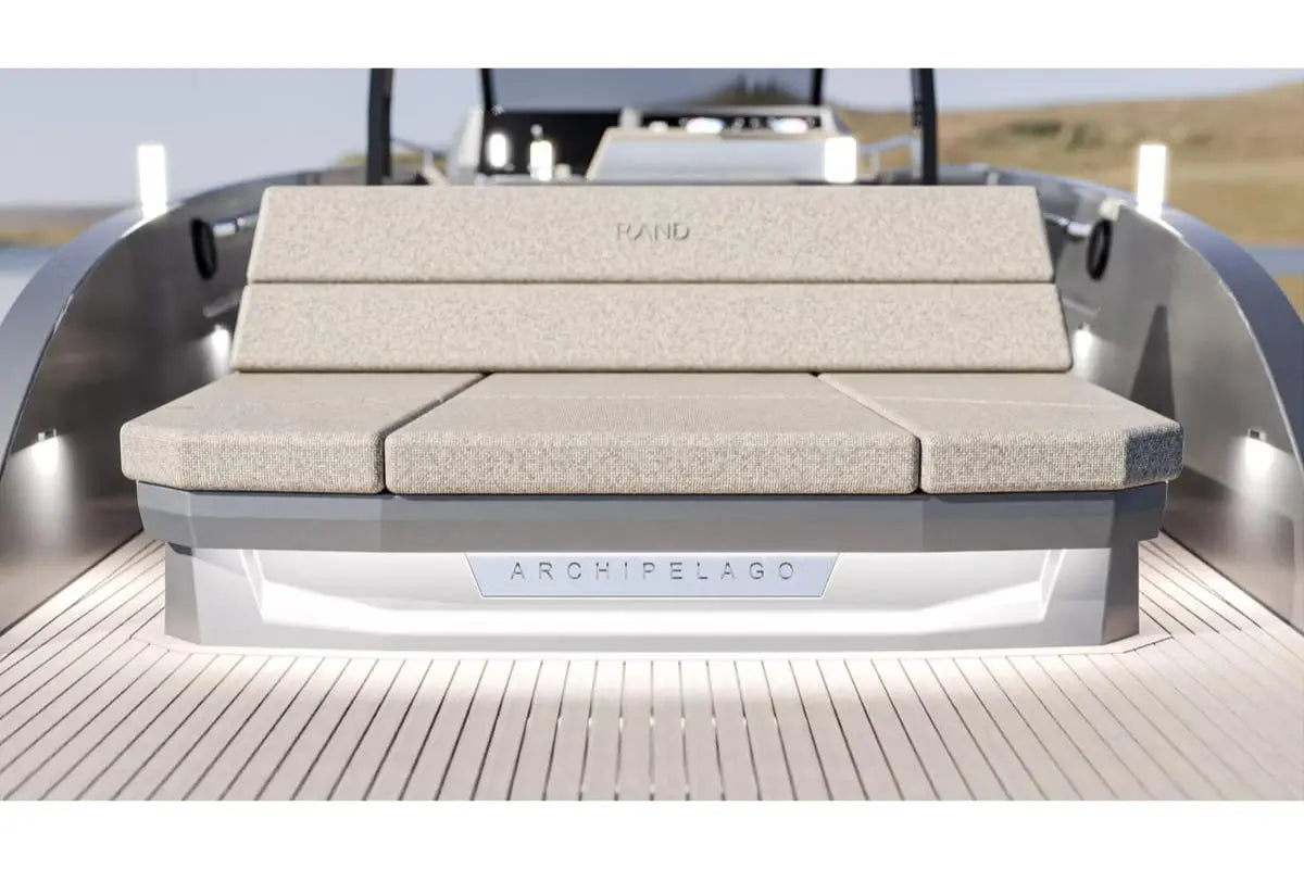 Beige outdoor sofa on Rand Archipelago 32 Electric Boat with 'Archipelago' branding, set against a blurred natural background.