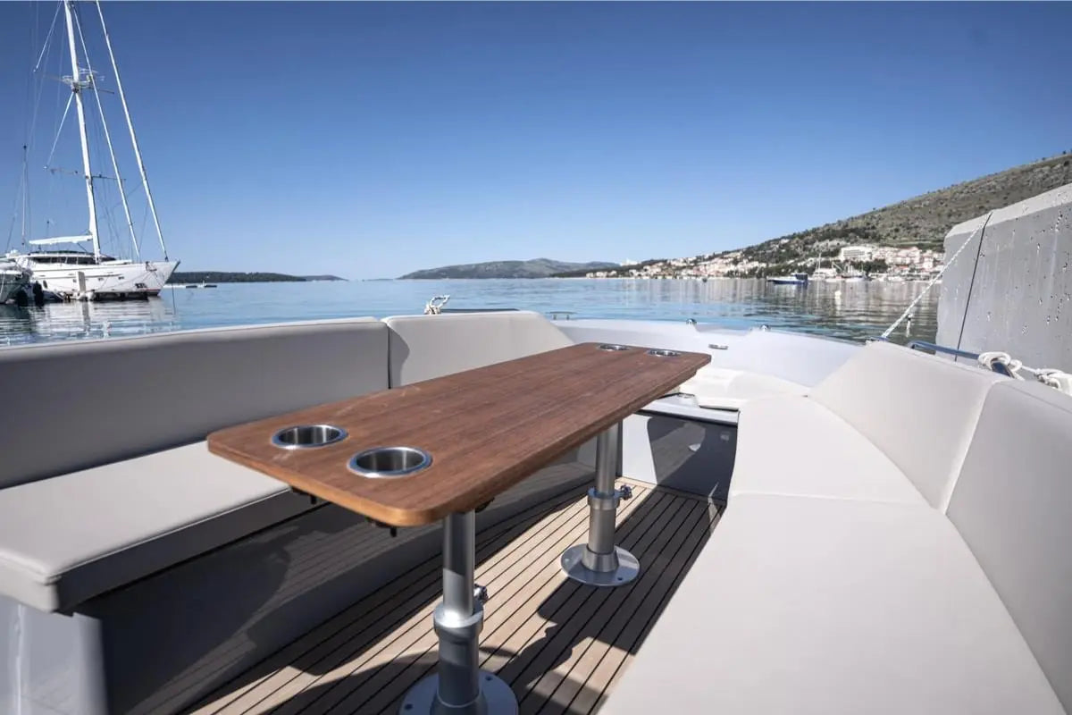 Wooden table on Rand Breeze 20 Electric Boat deck with a scenic background of water and sky.