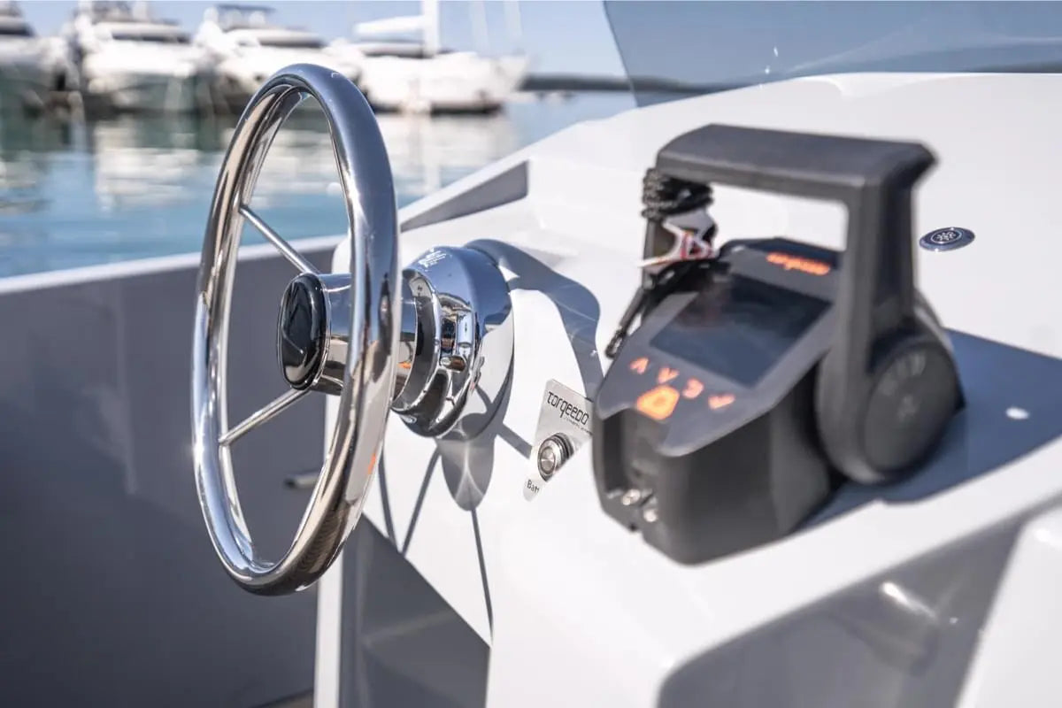 Close-up of Rand Breeze 20 Electric Boat steering wheel and control panel with a marina background.