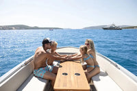 Family of four on Rand Mana 24 Electric Boat in the water with clear blue skies.