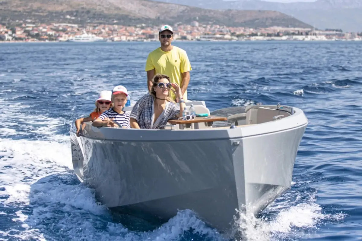 Family on Rand Mana 24 Electric Boat in the open water with a coastal town in the background