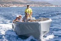 Family on Rand Mana 24 Electric Boat in the open water with a coastal town in the background
