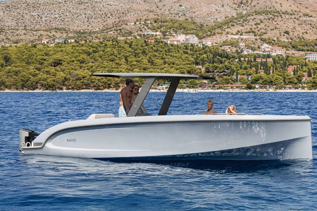 White Rand Mana 24 Electric Boat on a body of water with a scenic background
