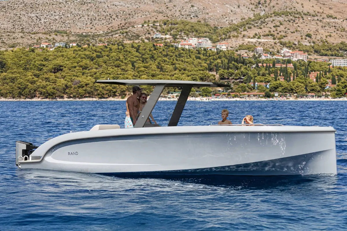 Rand Mana 24 Electric Boat on blue water with a scenic background
