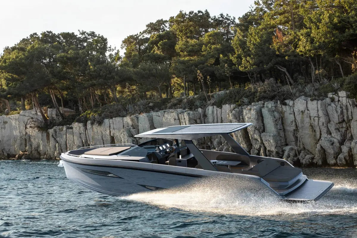 Rand Realm 44 Electric Boat on a body of water with a rocky shoreline and trees in the background