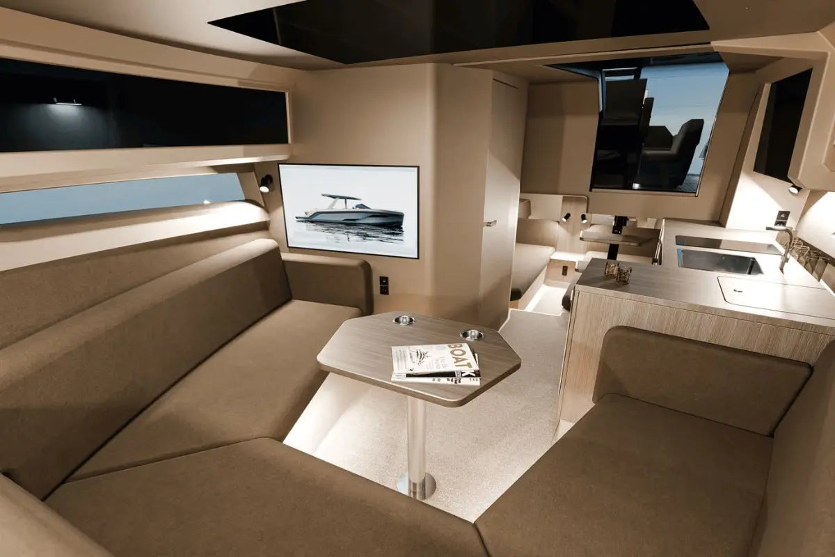 Luxury Rand Realm 44 Electric Boat interior with beige couch, table, and large screen displaying a boat.