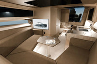 Luxury Rand Realm 44 Electric Boat interior with beige couch, table, and large screen displaying a boat.