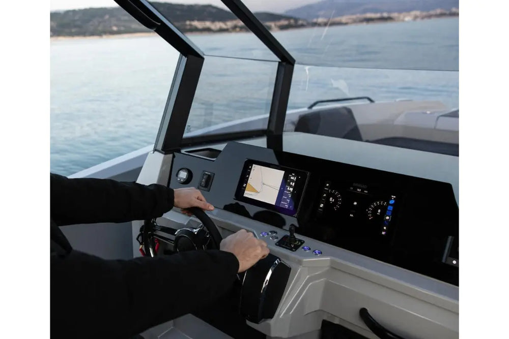 Person operating Rand Roamer 29 Electric Boat with a dashboard and screen on a body of water.