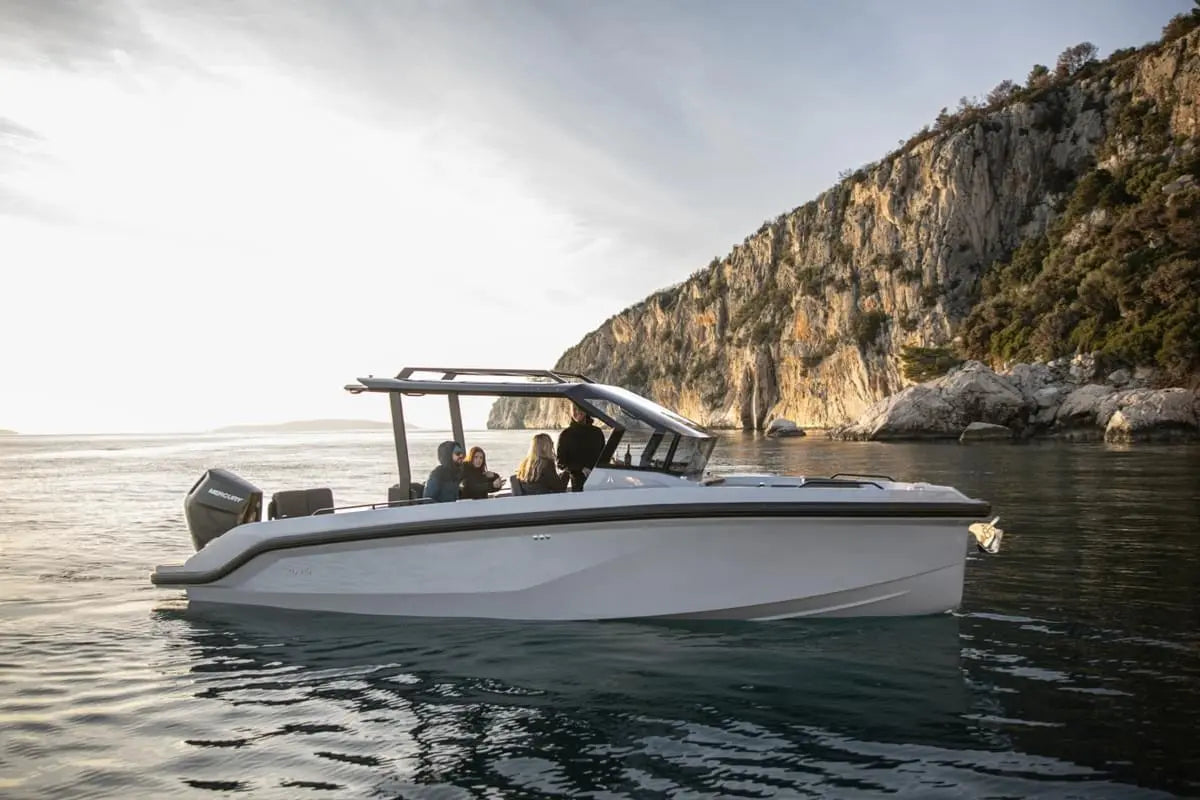 White Rand Roamer 29 Electric Boat on water with a scenic background of cliffs and sky.