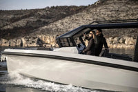 Two people on Rand Roamer 29 Electric Boat in a scenic outdoor setting with mountains.