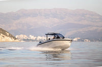 Rand Roamer 29 Electric Boat on water with mountains and buildings in the background