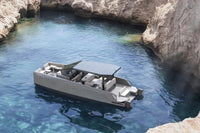 Rand Solara 33 Electric Boat docked in a rocky cove with clear blue water