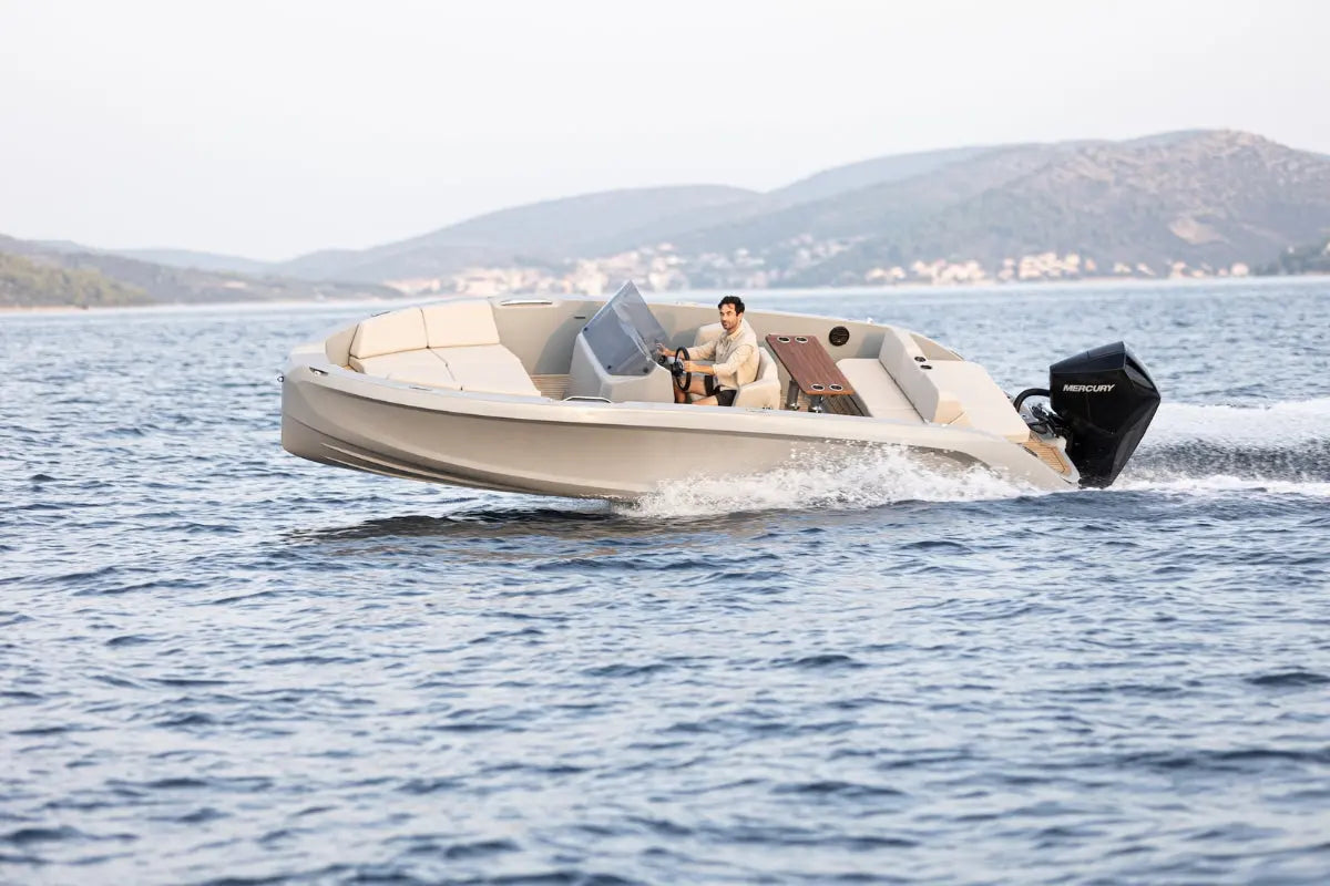 Person driving Rand Source 22 Electric Boat on a body of water with mountains in the background