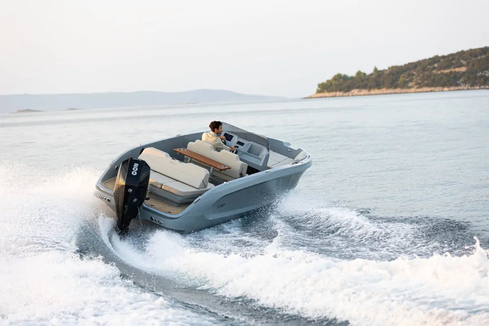 Rand Source 22 Electric Boat on a body of water with a person inside, surrounded by a scenic landscape.