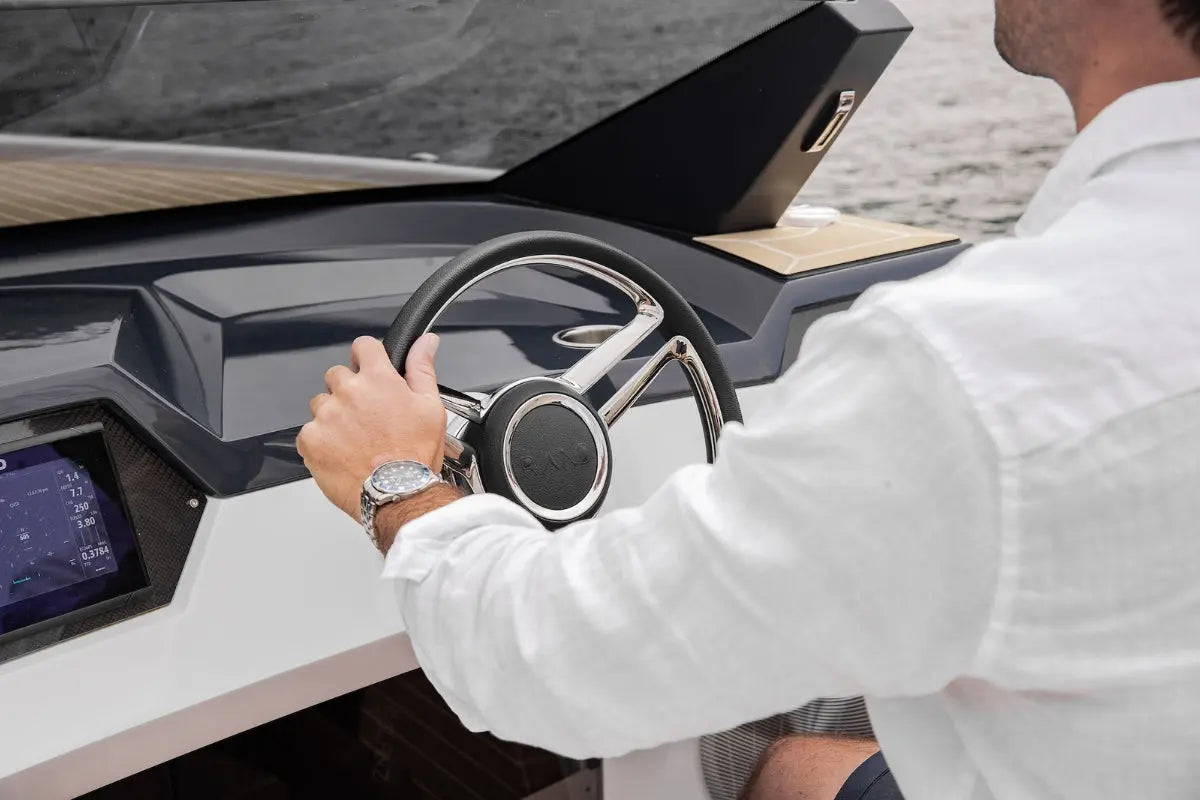 Person inside a luxury Rand Spirit 25 Electric Boat, holding the steering wheel.