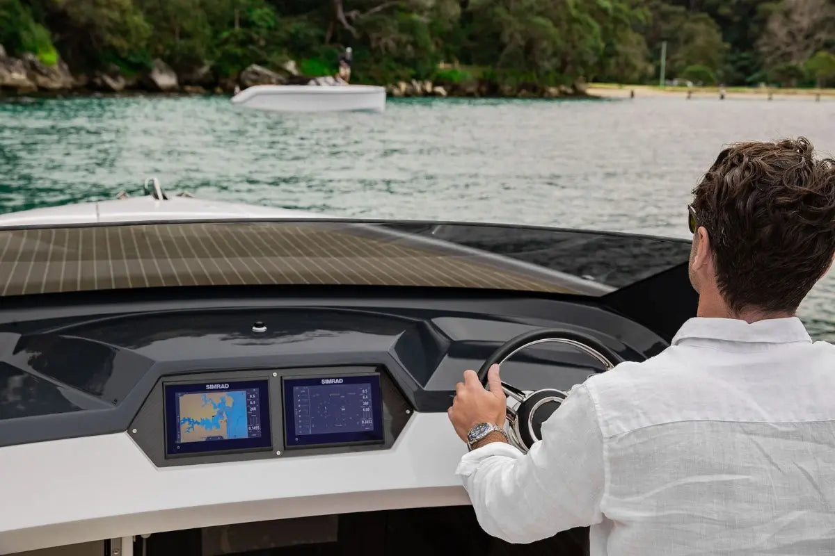 Person operating Rand Spirit 25 Electric Boat with a dashboard and screens on a body of water.