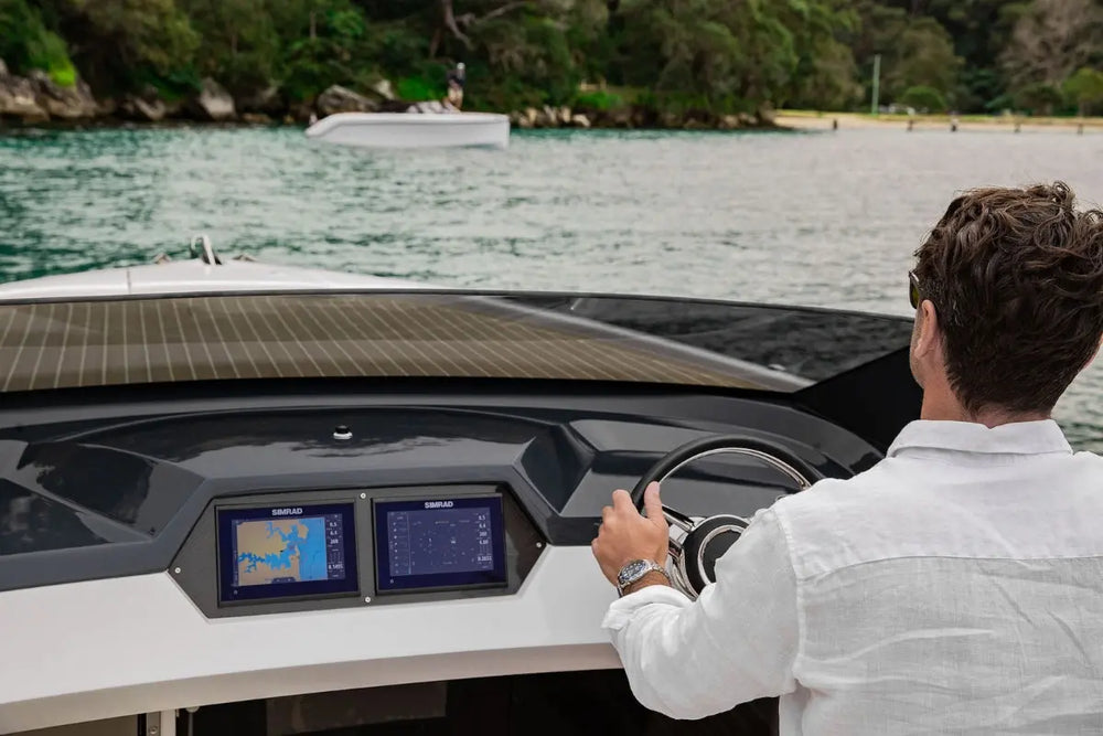 Person operating Rand Spirit 25 Electric Boat with a dashboard and screens on a body of water.