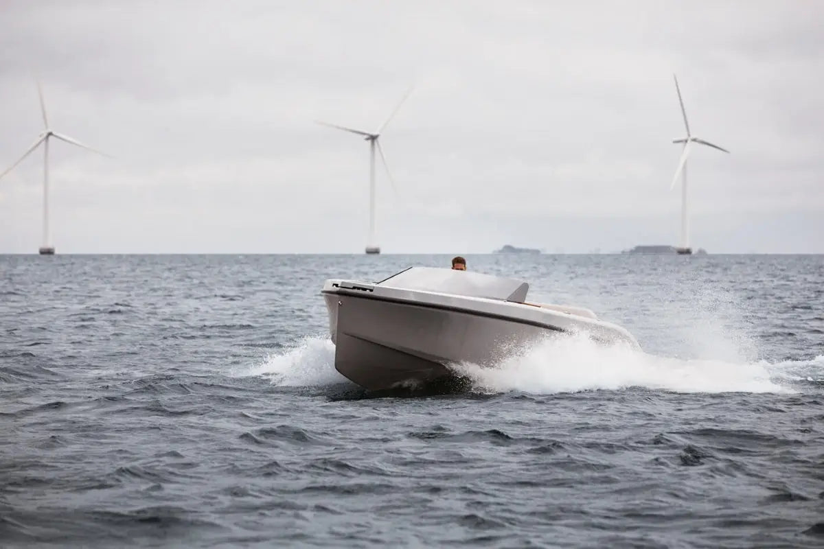 Rand Spirit 25 Electric Boat speeding on water with wind turbines in the background