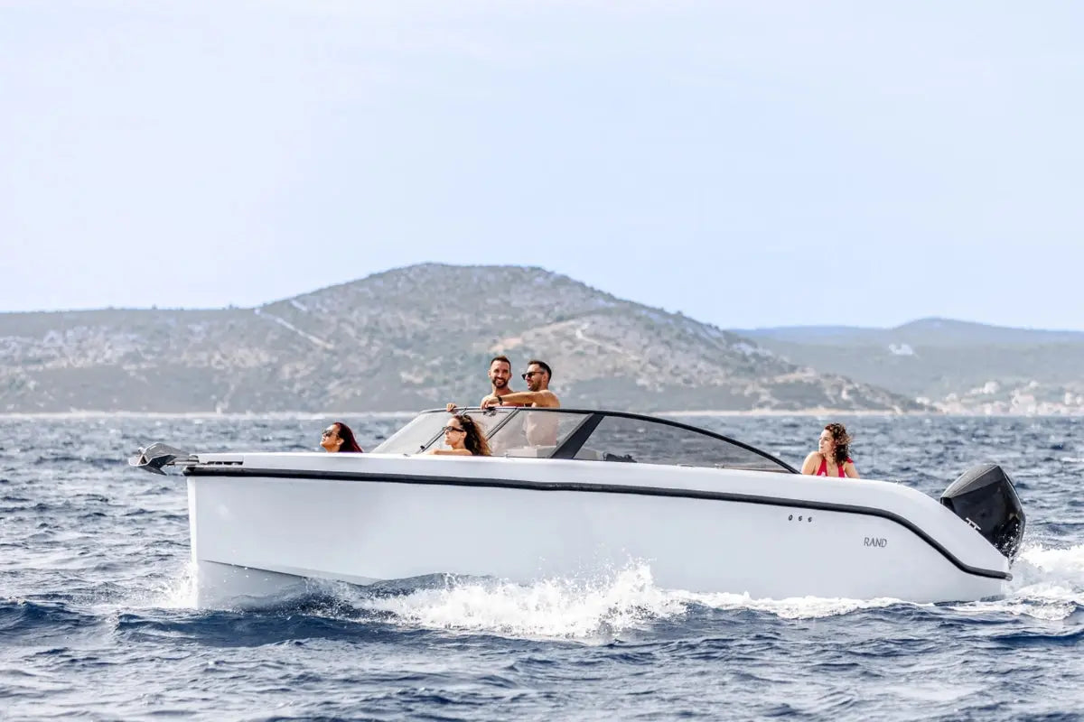 White Rand Supreme 27 Electric Boat with passengers on a body of water with mountains in the background