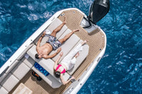 Two people relaxing on Rand Supreme 27 Electric Boat in the middle of a blue ocean.