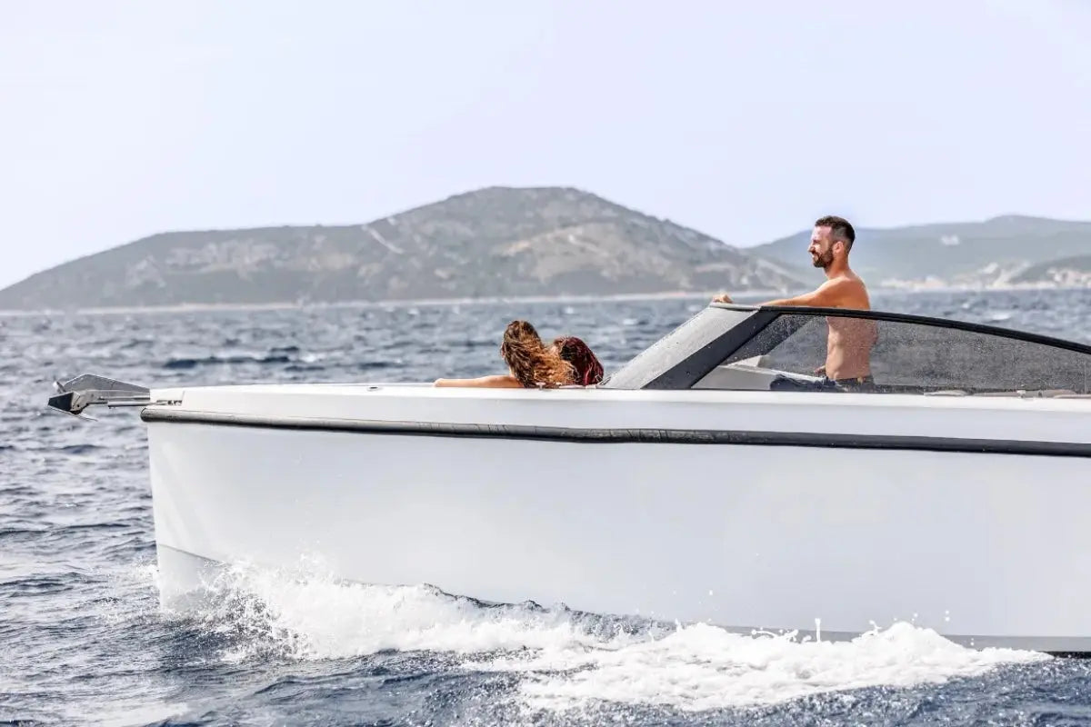 Two people on Rand Supreme 27 Electric Boat in the ocean with mountains in the background