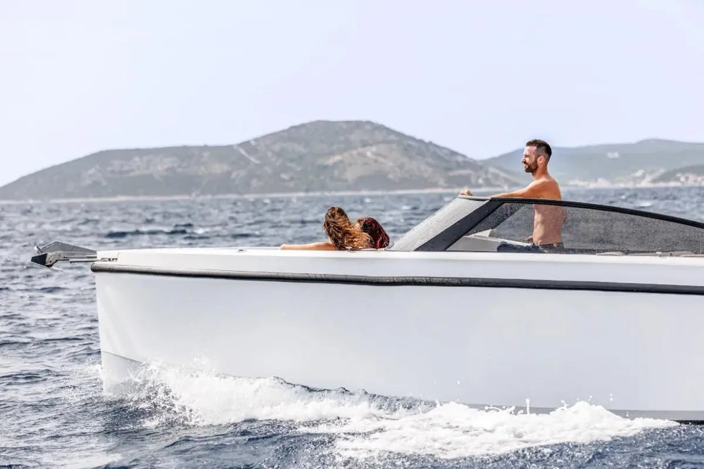 Two people on Rand Supreme 27 Electric Boat in the ocean with mountains in the background