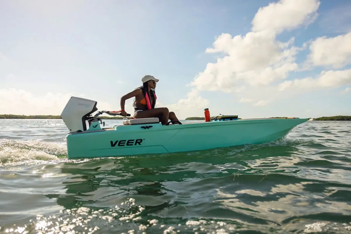 Person on a teal Veer V13 Electric Boat in the water with a clear sky.