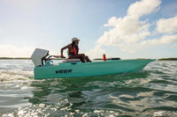 Person on a teal Veer V13 Electric Boat in the water with a clear sky.