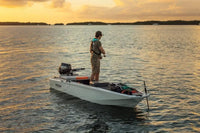 Man standing on Veer V13 Electric Boat on calm water at sunset