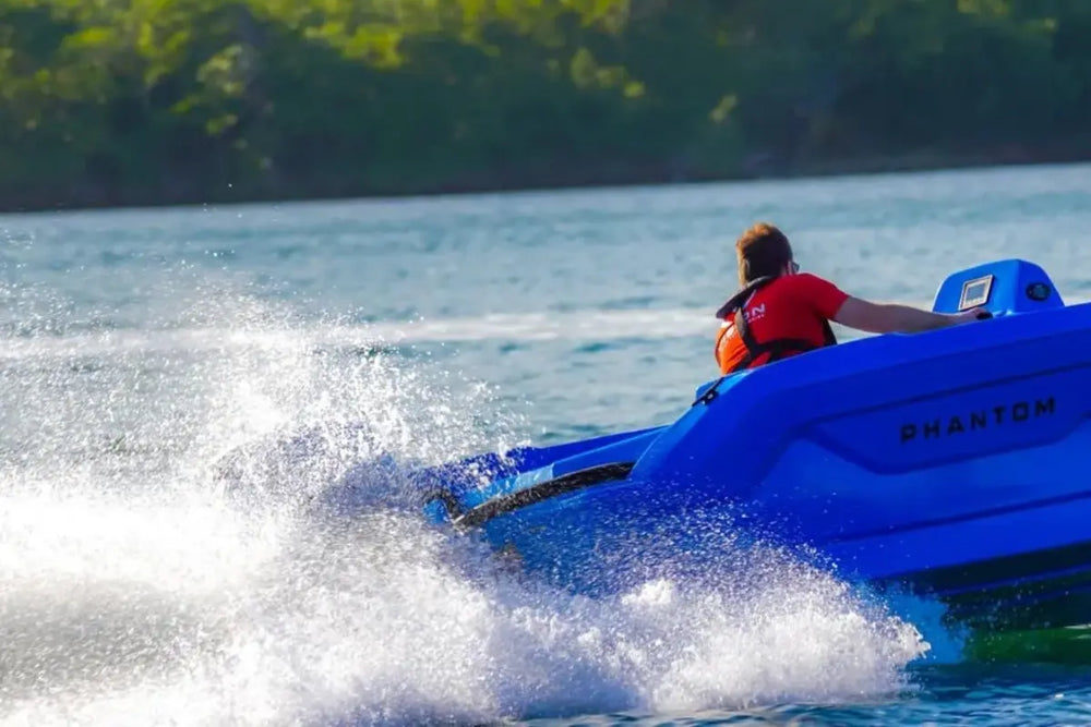 Person riding Vision Phantom Electric Boat on a lake with trees in the background