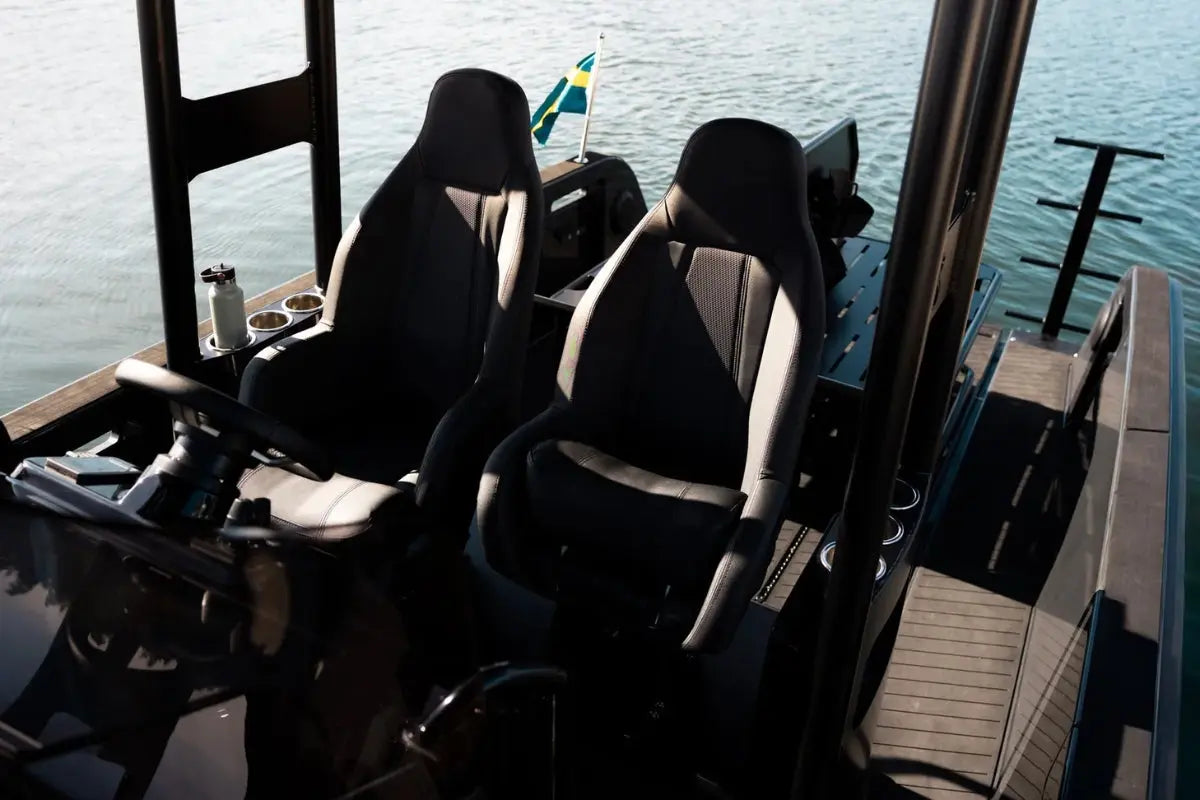 Two black and gray seats on X Shore Pro Electric Boat with water in the background